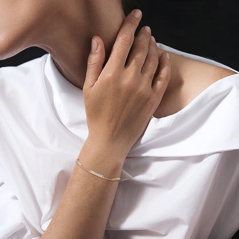 Close-up of a person wearing a gold bracelet on a white background
