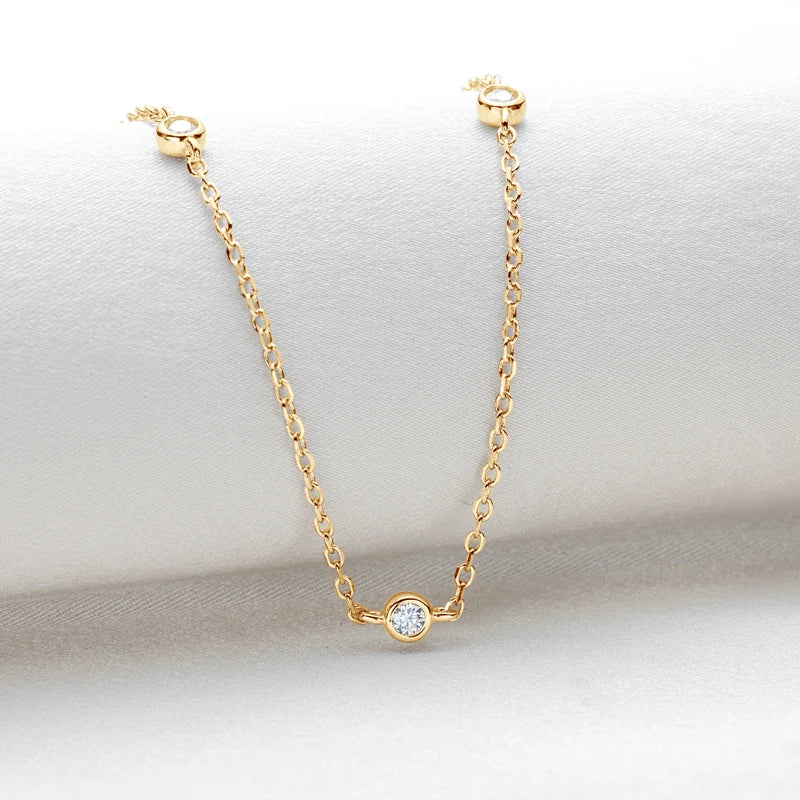 Gold necklace with a small round pendant on a light gray background