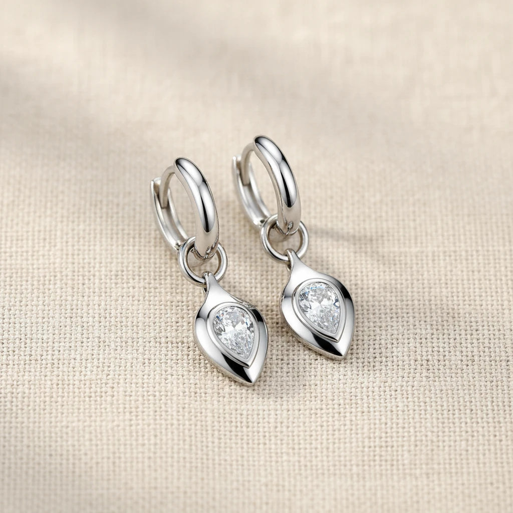 Silver earrings with heart-shaped gemstones on a light blue background