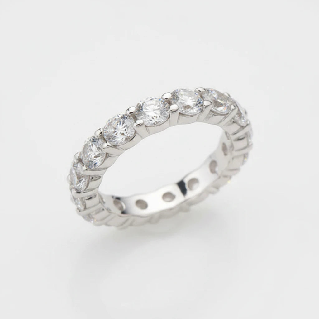 Silver ring with clear gemstones on a white cushion