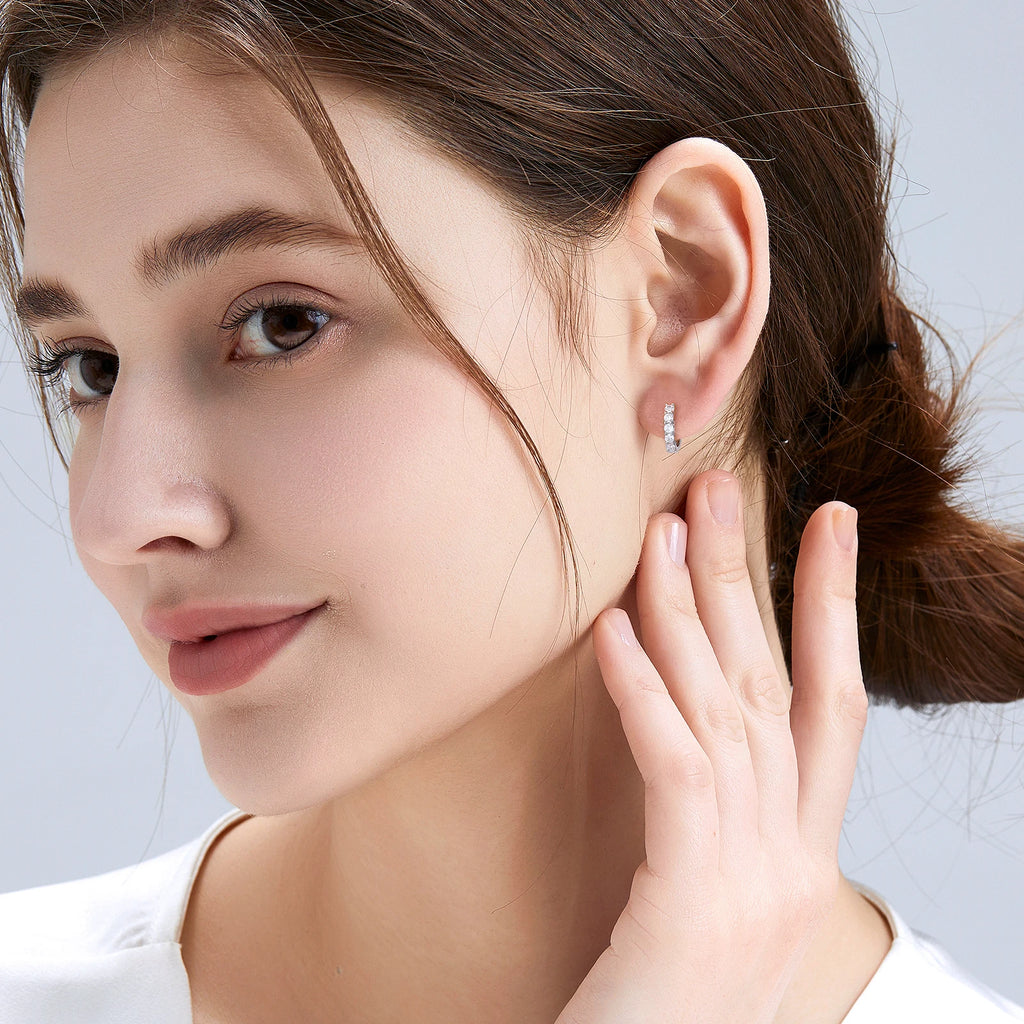 Close-up of a woman wearing a silver earring with a light gray background