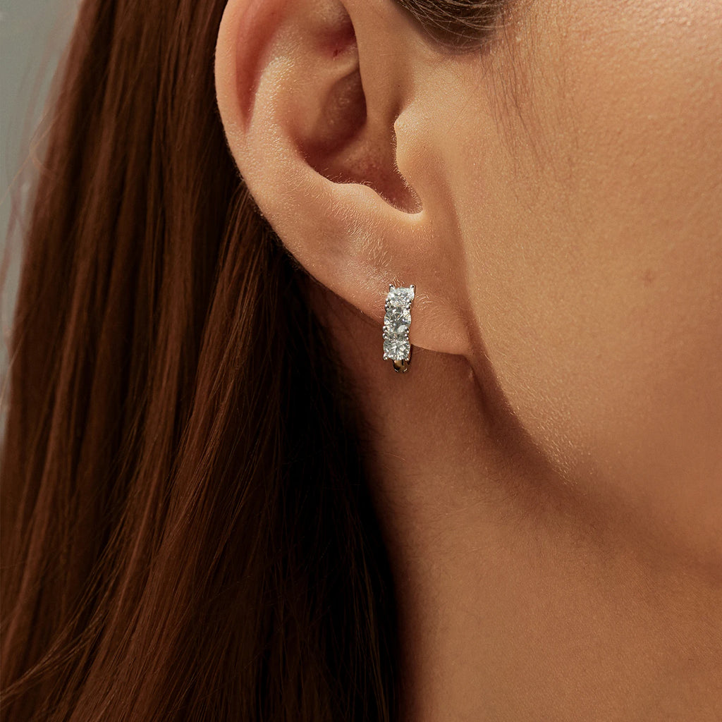 Close-up of an ear wearing a diamond earring with a neutral background