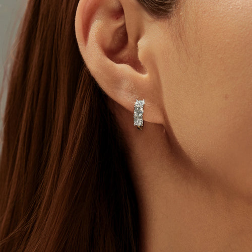 Close-up of an ear wearing a diamond earring with a neutral background