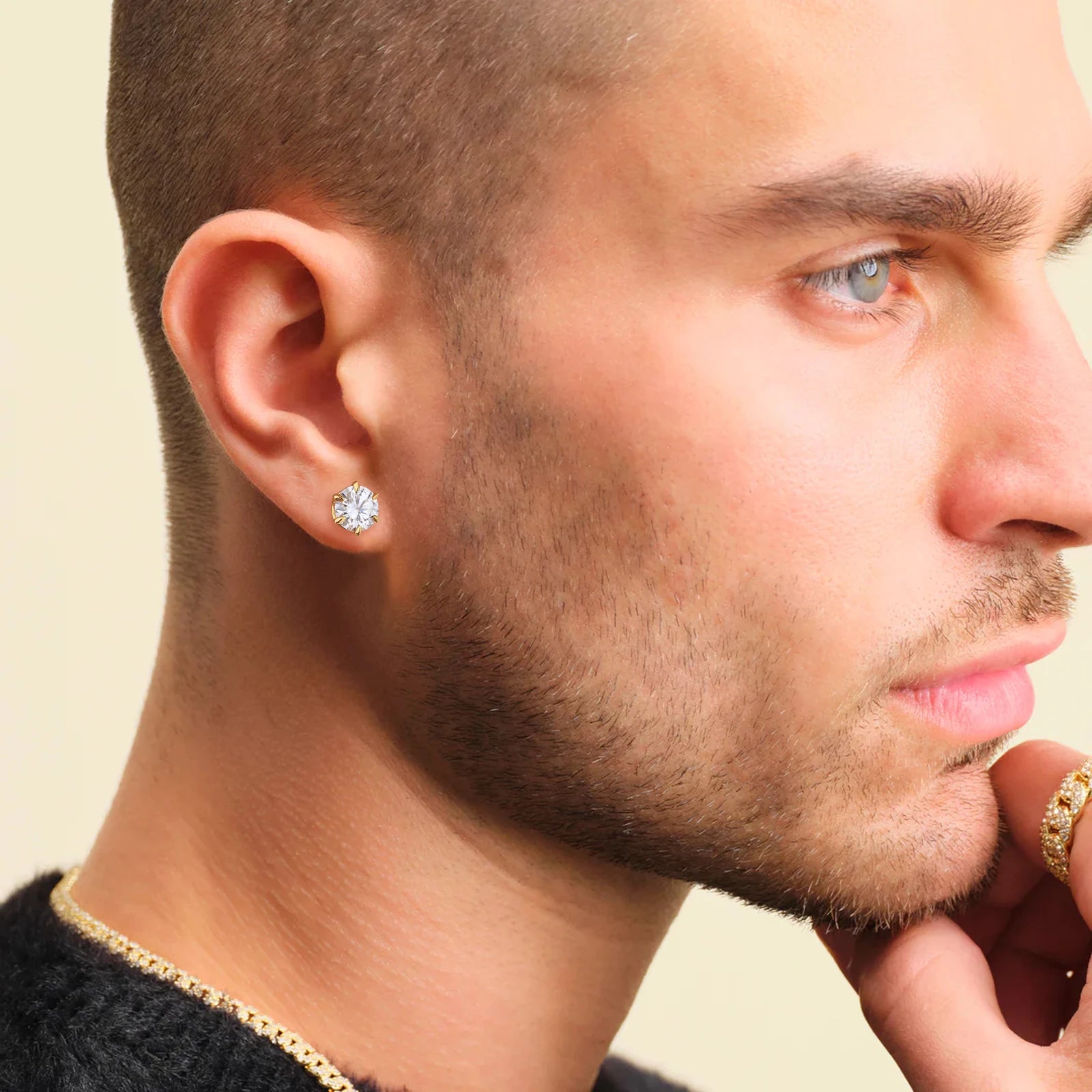 Close-up of a man wearing diamond earrings with a neutral background