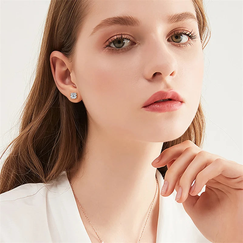 Close-up of a woman wearing diamond earrings with a plain background