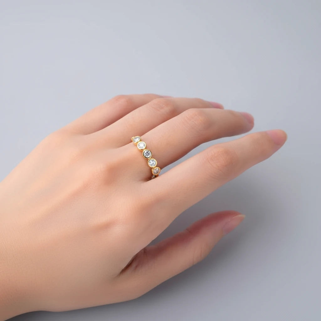 Hand wearing a gold ring with small diamonds on a light background