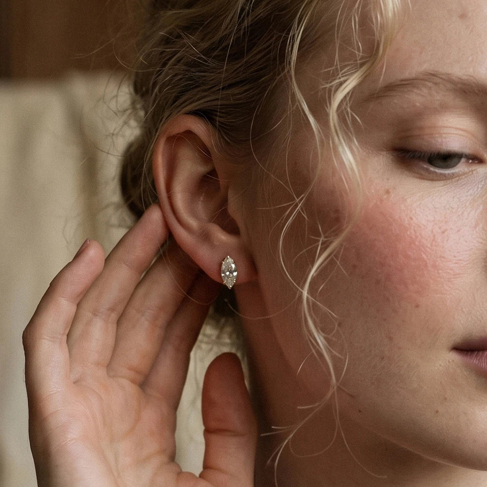 Close-up of a person wearing an earring with a hand adjusting it.