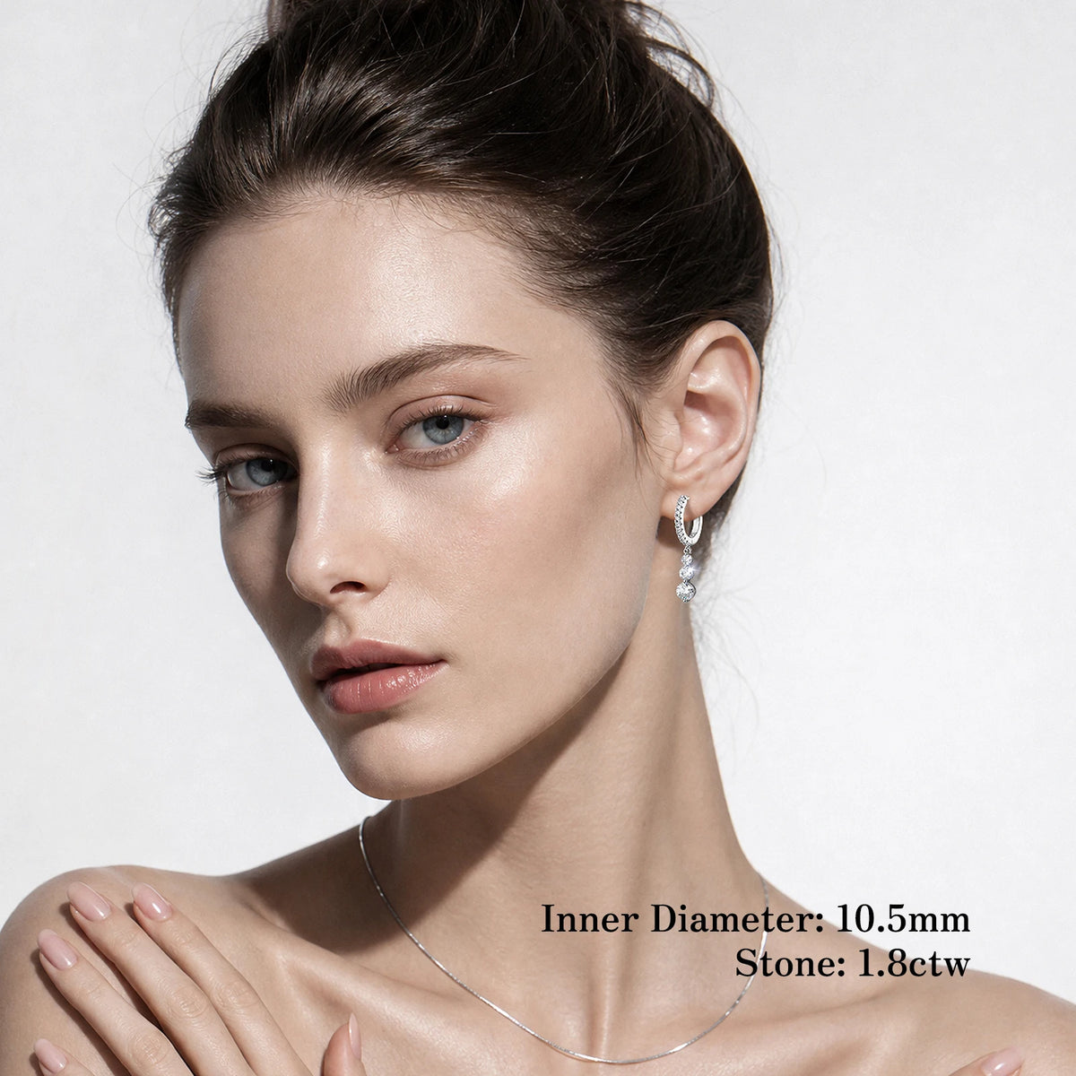A close-up of a woman wearing a delicate silver necklace and matching drop earring against a light gray background, with text overlay detailing the earring's dimensions.
