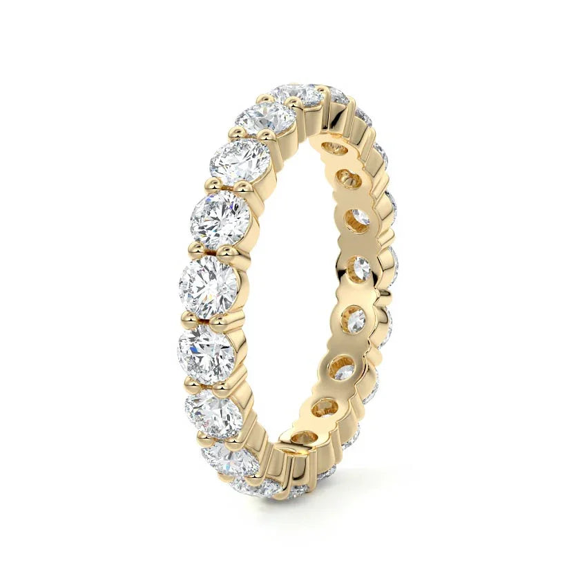 A yellow gold eternity ring featuring a continuous row of round-cut clear gemstones in a prong setting, shown on a clean white background.