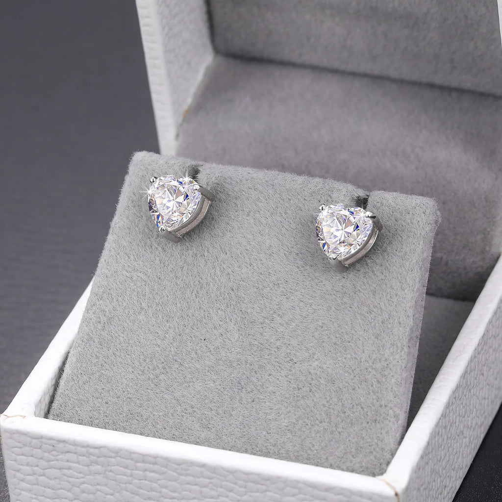 Pair of diamond stud earrings on a gray cushion in a jewelry box.