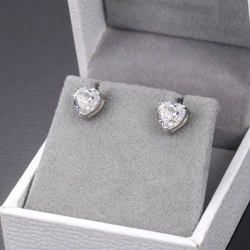 Pair of diamond stud earrings on a gray cushion in a jewelry box.