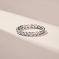 Silver ring with embedded diamonds on a beige background