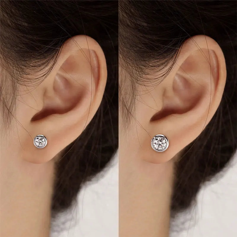 Close-up of two ears wearing silver stud earrings on a neutral background