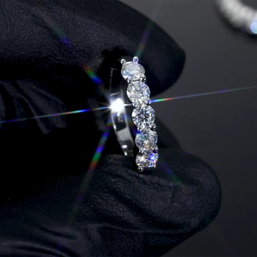 Moissanite hoops held by a gloved hand with a dark background