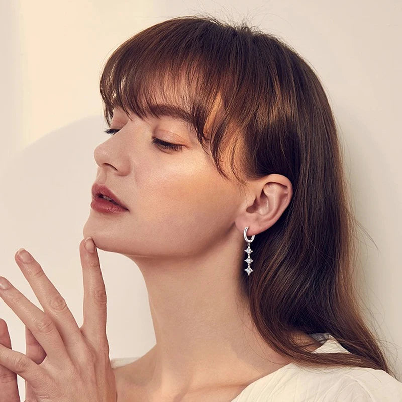 Woman with a soft smile, wearing a gold earring, against a neutral background