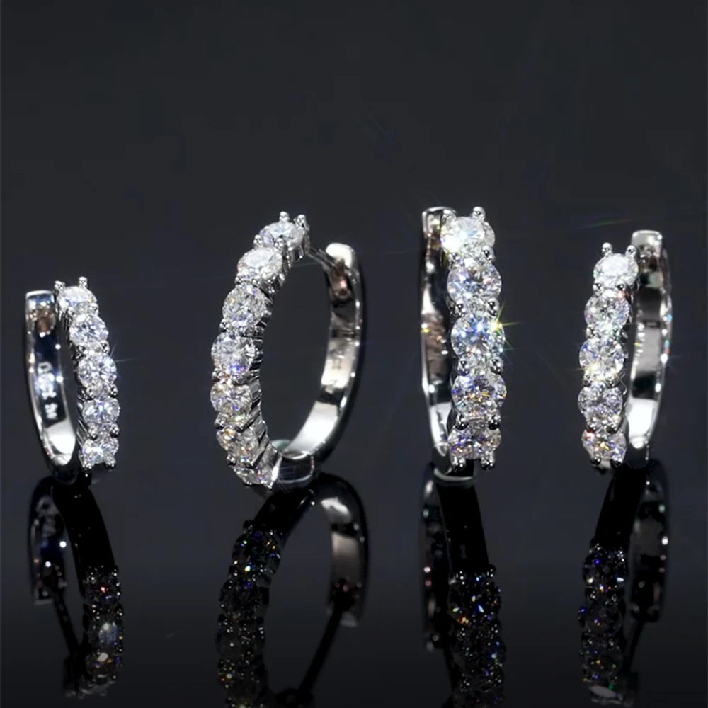 Set of silver hoop earrings with clear gemstones on a black background