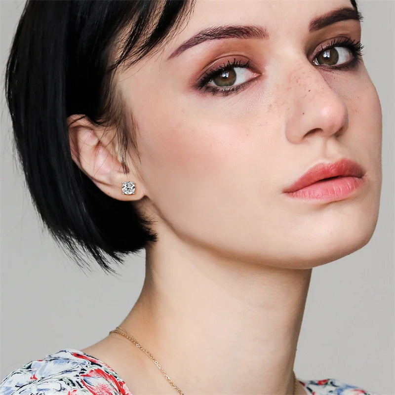 Close-up of a woman wearing a diamond earring with a plain background