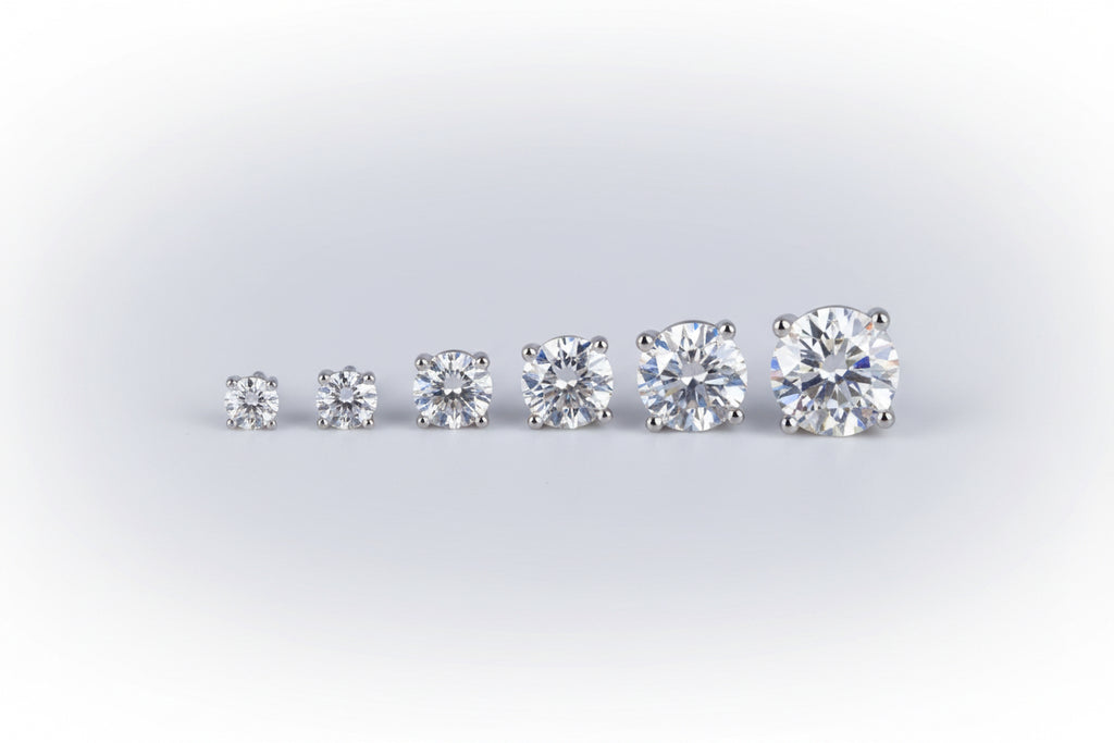 Pair of diamond stud earrings on a reflective black surface