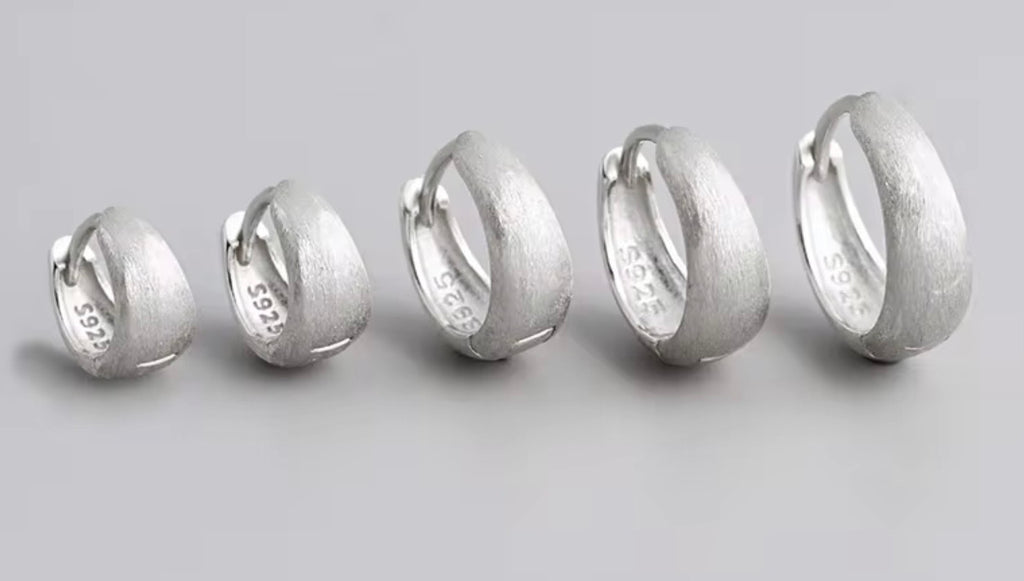 Five textured silver hoop rings of varying sizes arranged in a row on a light gray background. The inner band of the rings is stamped with '925' and 'S925'.