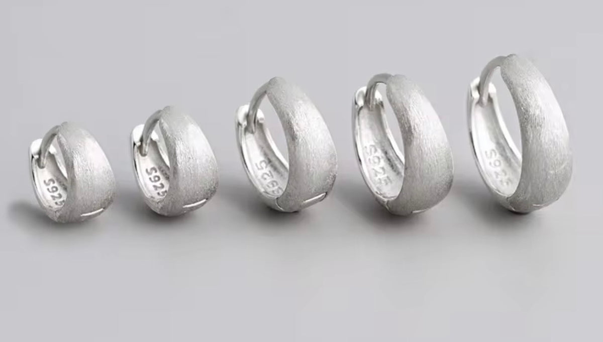 Five textured silver hoop rings of varying sizes arranged in a row on a light gray background. The inner band of the rings is stamped with '925' and 'S925'.