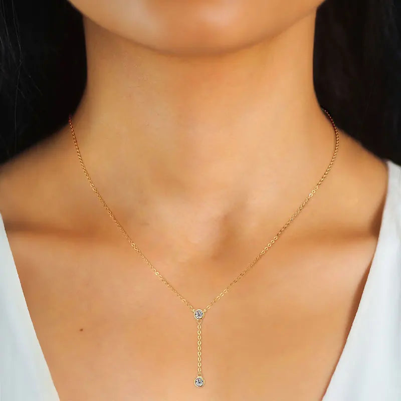 Gold necklace with a pendant on a model wearing a white top